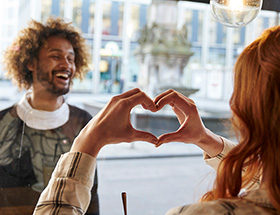 femme faisant un coeur a un homme aux cheveux frisés